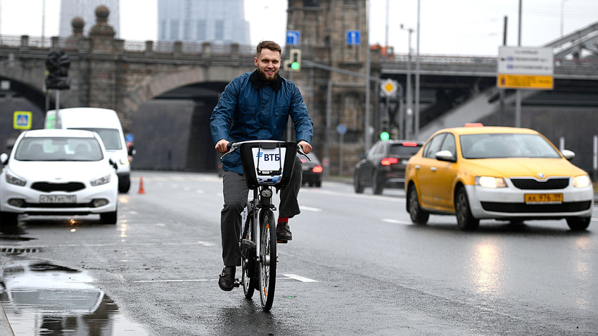 A young man rides a public bike on a Moscow street. 