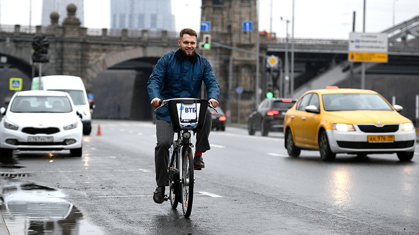 Homem anda em bicicleta pública por rua moscovita.