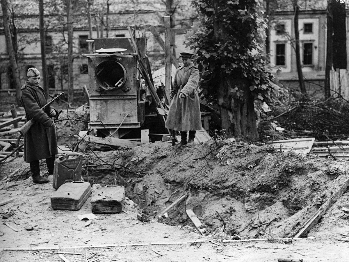 Deux soldats russes montrent ce que l'on pense être la tombe d'Hitler, derrière la Chancellerie de Berlin, près de jerricans d'essence