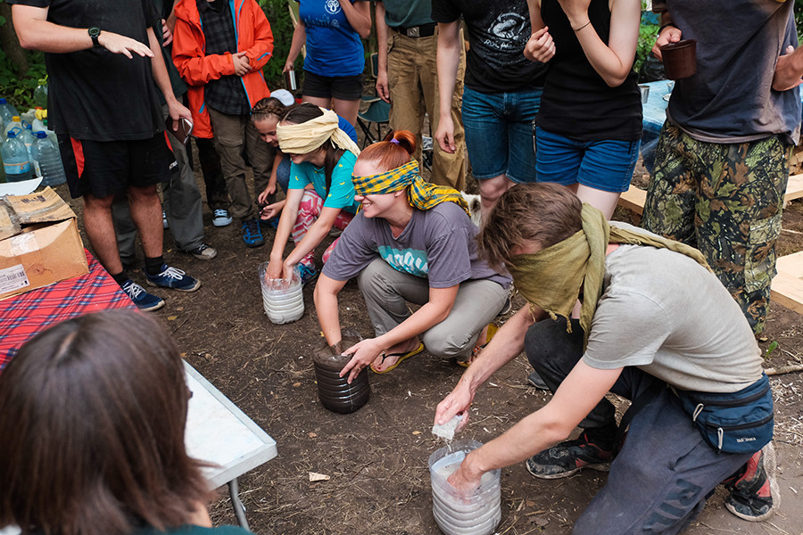 Jovens arqueólogos à procura de algo precioso em potes de água suja.