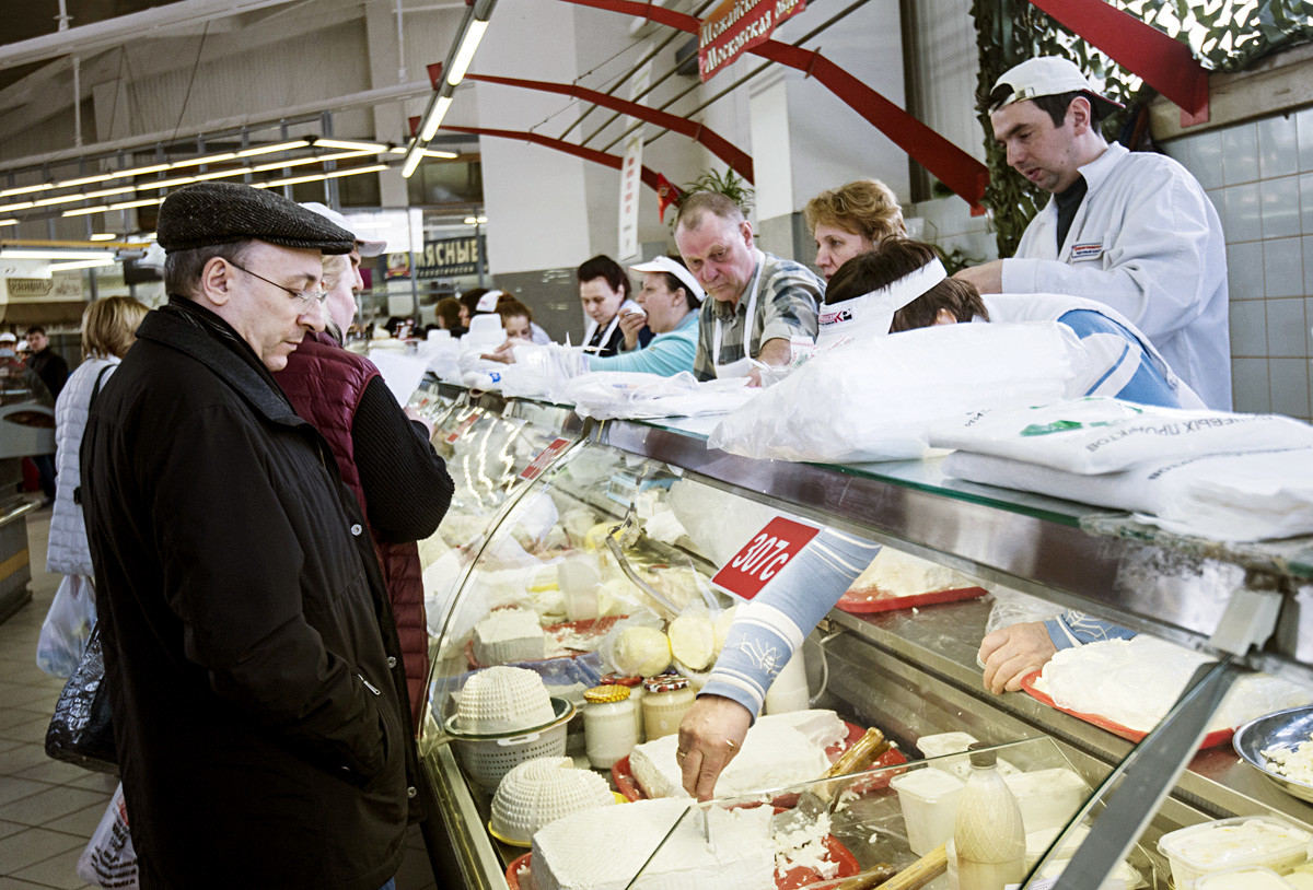 モスクワのドロゴミロフスキー市場にある乳製品コーナーの客と店員。