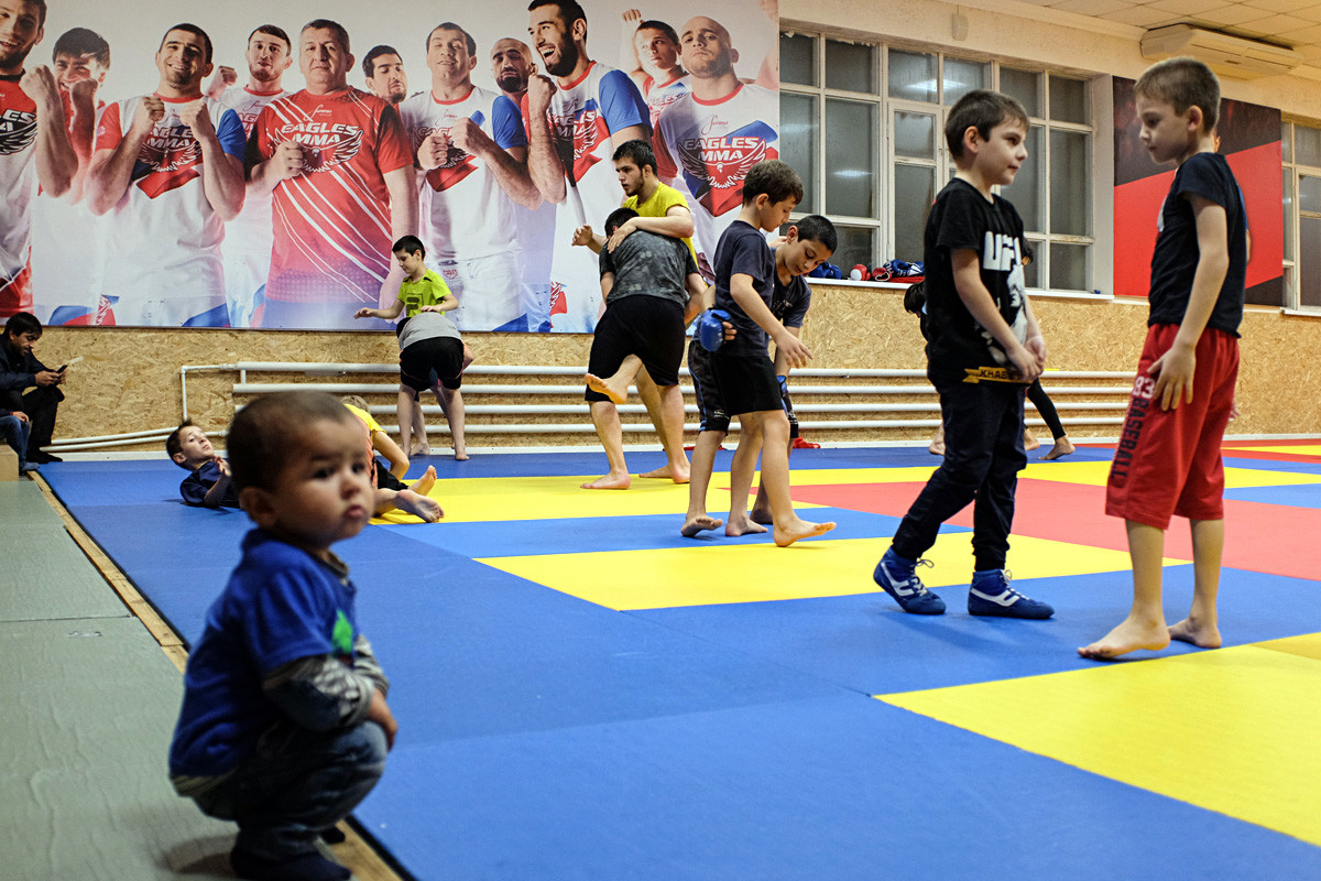 Orang-orang Dagestan menekuni gulat gaya bebas dan MMA sejak bayi. Ayah dan sekaligus pelatih Khabib Nurmagomedov, Abdulmanap Nurmagomedov, tampak pada poster mengenakan kaus merah.