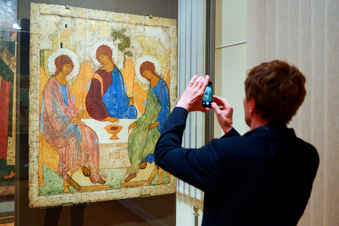 A young man taking photo of Andrei Rublev's Icon of the Holy Trinity (1425–1427) at the Tretyakov State Gallery.