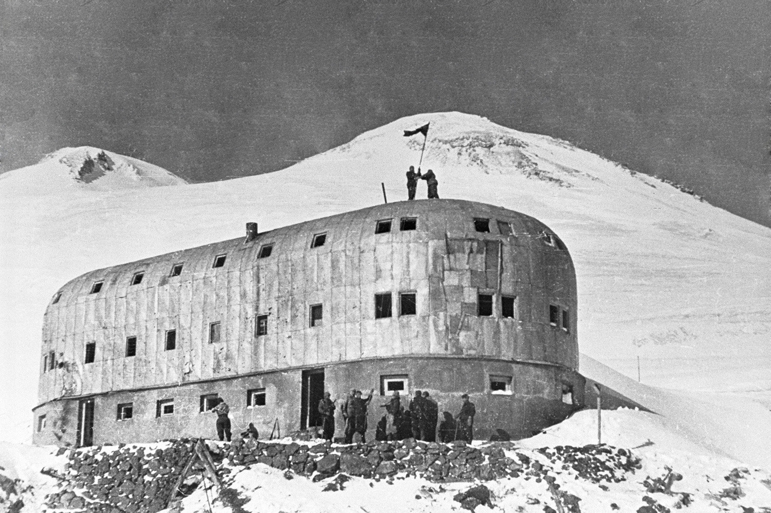 Војници го поставуваат советското знаме на станицата „Засолништето на единаесеттемина“ на планината Елбрус, 1943.