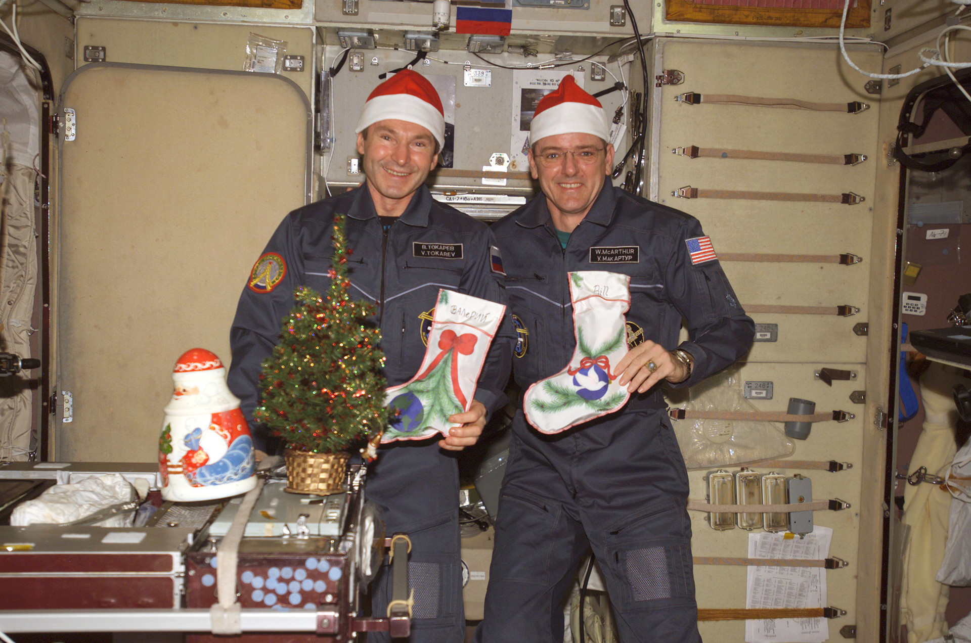 Астронавт Уильям С. Макартур-младший (справа) и командир экспедиции и научный сотрудник космической станции NASA Валерий Иванович Токарев позируют для праздничной фотографии в сервисном модуле 