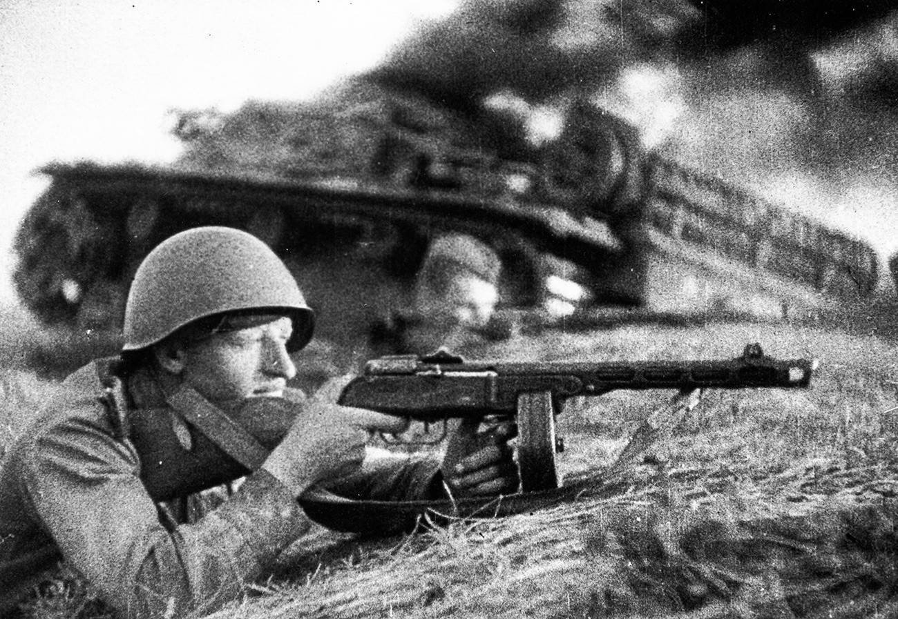 Soldados empunham metralhadoras em frente a tanque que quase penetrou nas linhas de frente soviéticas. 1942.