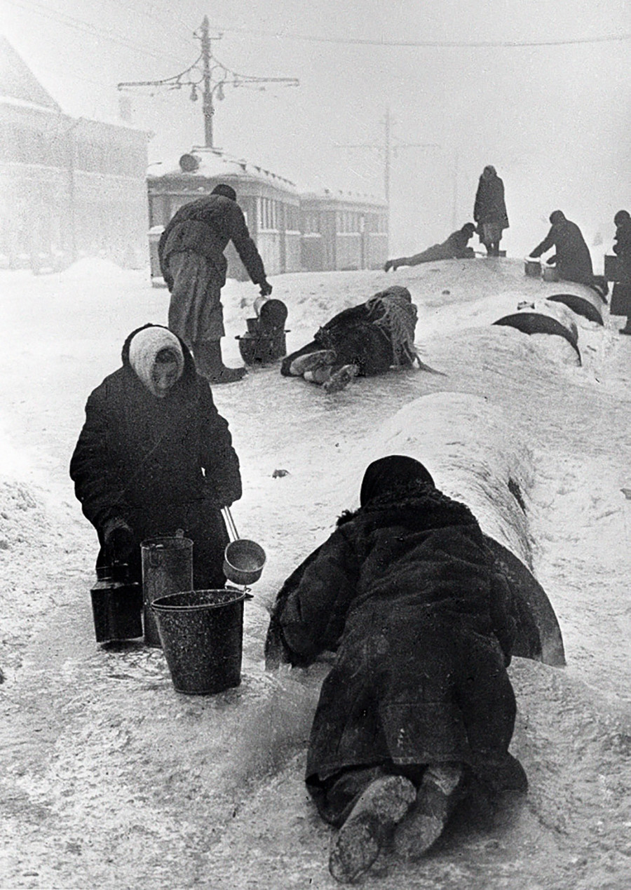 Moradores de Leningrado coletam água de tubulação rompida em rua coberta de neve