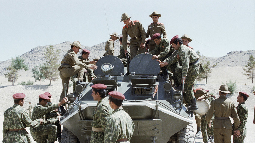 Советски војници им покажуваат на авганистански падобранци воена техника.