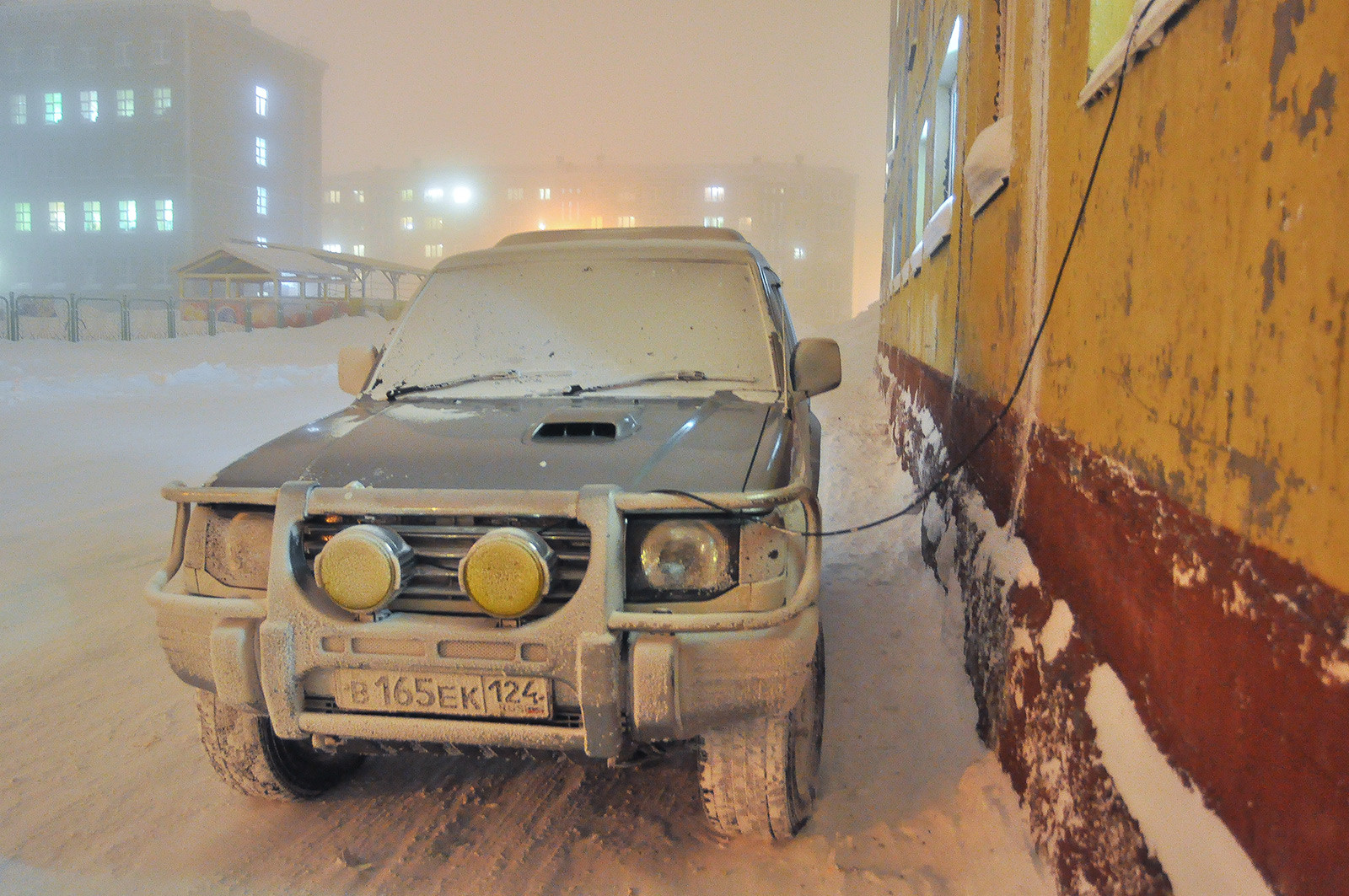 Зарядка аккумулятора автомобиля на одной из улиц Норильска во время мороза. 