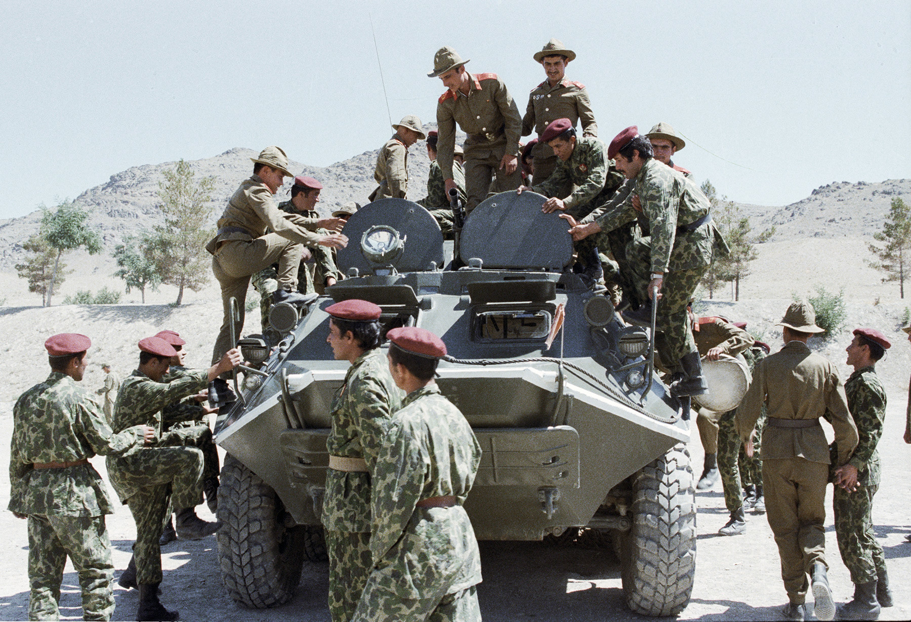 Soviet soldiers are showing their military equipment to Afghan paratroopers.

