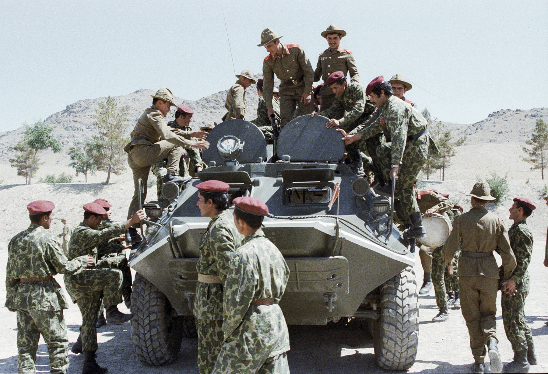 Soviet soldiers are showing their military equipment to Afghan paratroopers.
