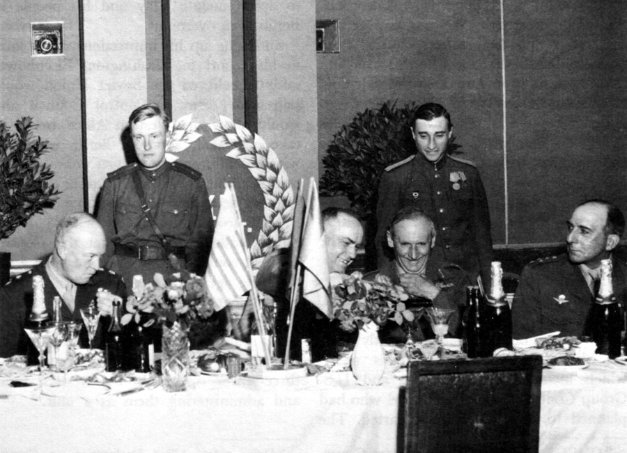 1945年6月5日。ゲオルギー・ジューコフ（中央）がバーナード・モントゴメリー（彼の右側）のグラスにシャンパンを入れる。左端にはドワイト・アイゼンハワーが座っている。