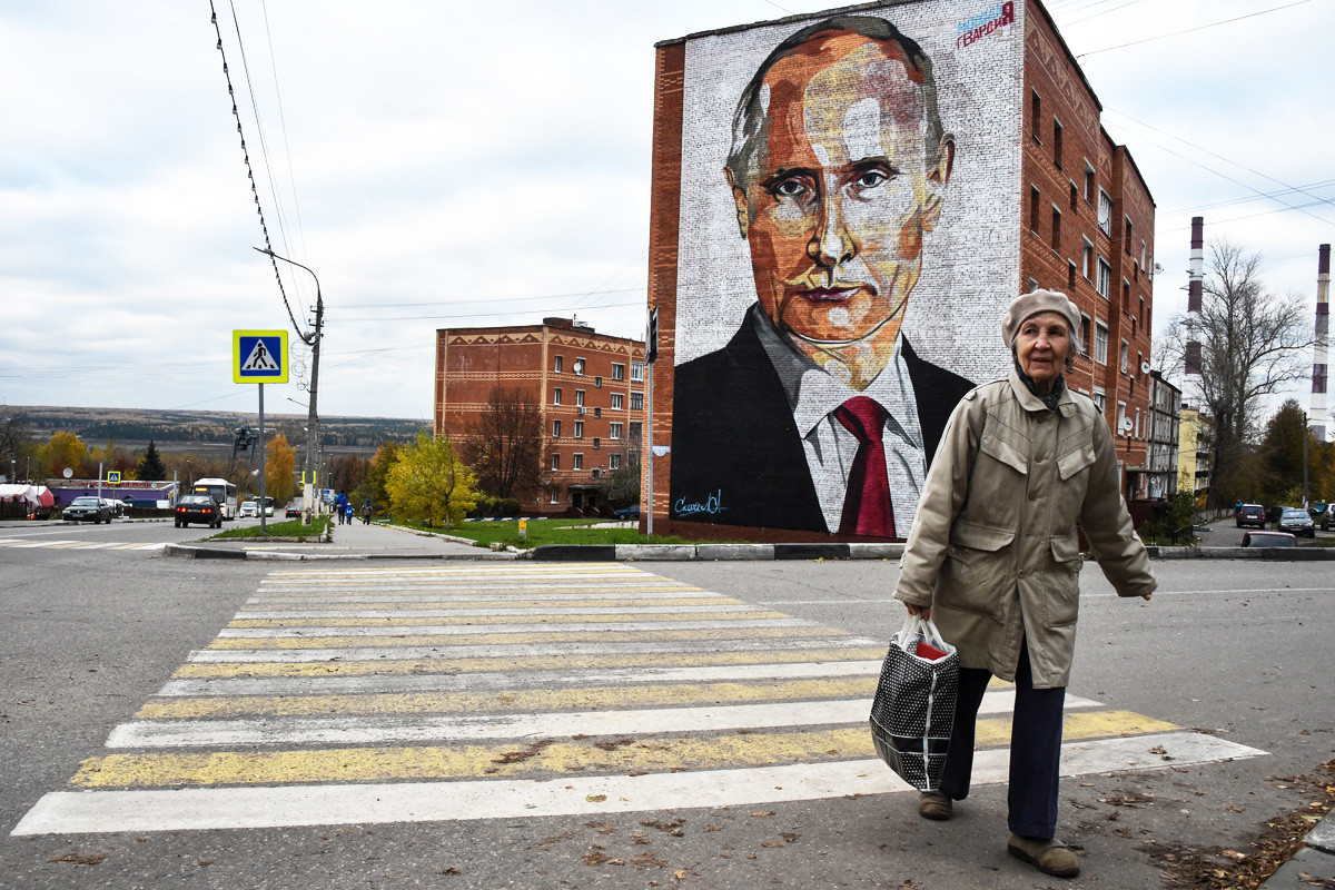 Anciana cruza la carretera frente a un mural de Putin en Kashira, pueblo situado a 115 km al sureste de Moscú. 16 de octubre de 2017.