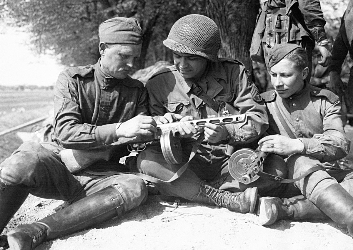 Амерички војник у друштву двојице руских војника упоређује наоружање после сусрета руских и америчких трупа на обали Елбе, Торгау, Немачка, 27. април 1945.