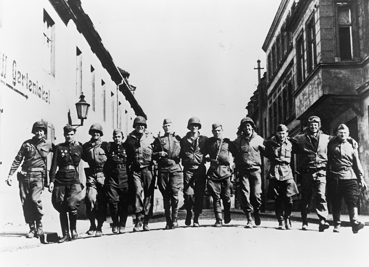 Nasmijani američki i ruski vojnici zagrljeni hodaju ulicom na obali Elbe, Njemačka, Drugi svjetski rat, 1945.