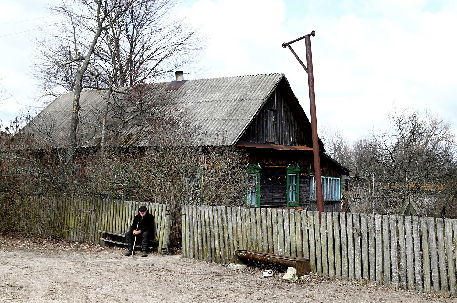 Иван Шамјанок, 90, седи пред својата куќа во селото Тулговичи, во близина на зоната на исклучување. Тој не сака да ја напушти својата земја.
