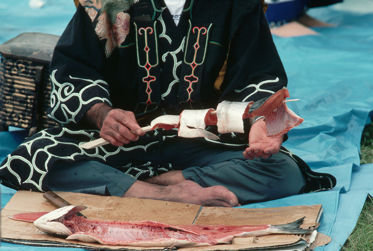 Претставник на народот Аину подготвува лосос на Првиот фестивал на лососот.