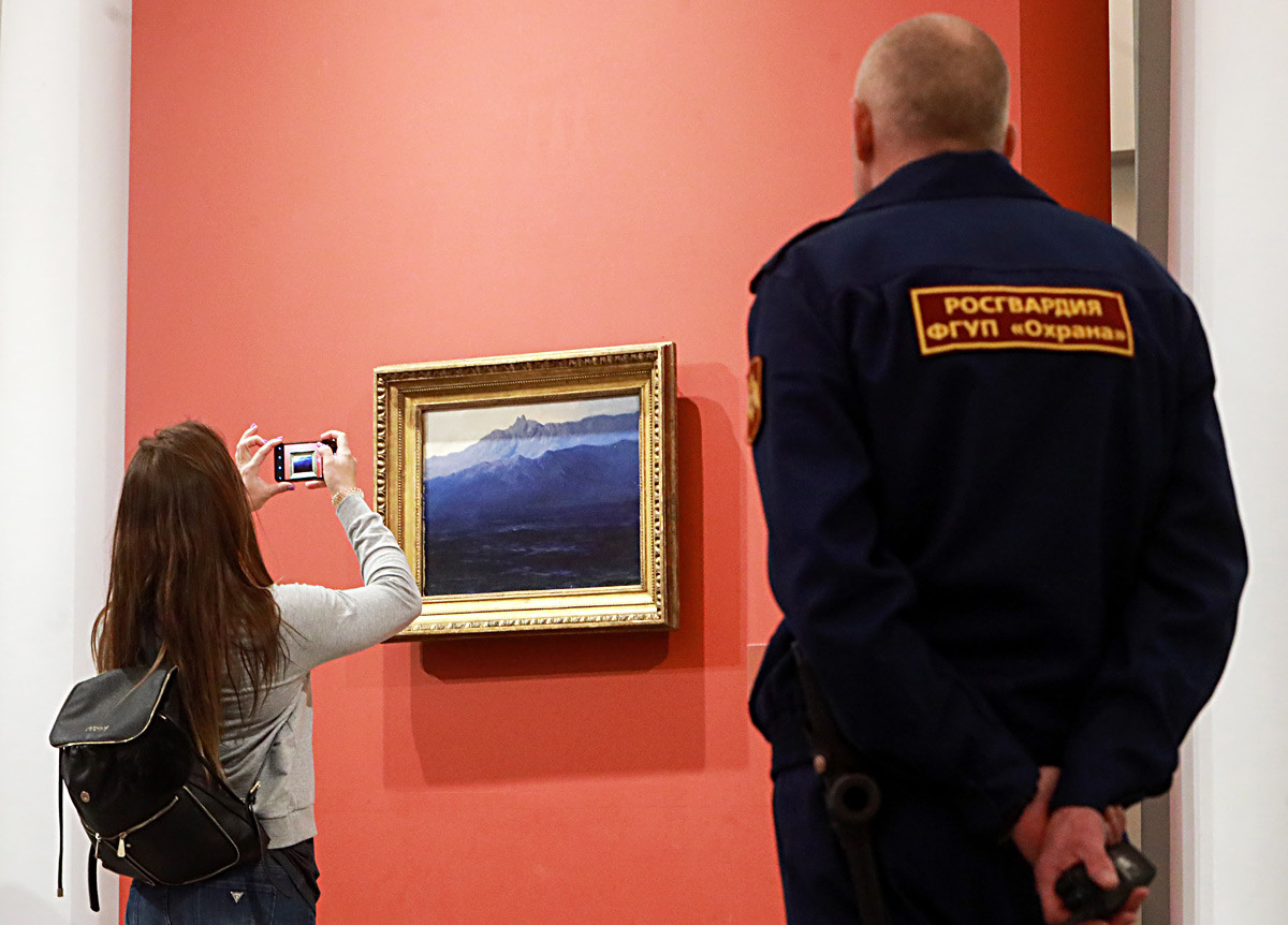 MARCH 22, 2019: A girl takes a picture of the Ai-Petri. Crimea painting on display at an exhibition of works by Russian painter Arkhip Kuindzhi held at the Mikhailovsky Palace, the main building of the State Russian Museum.