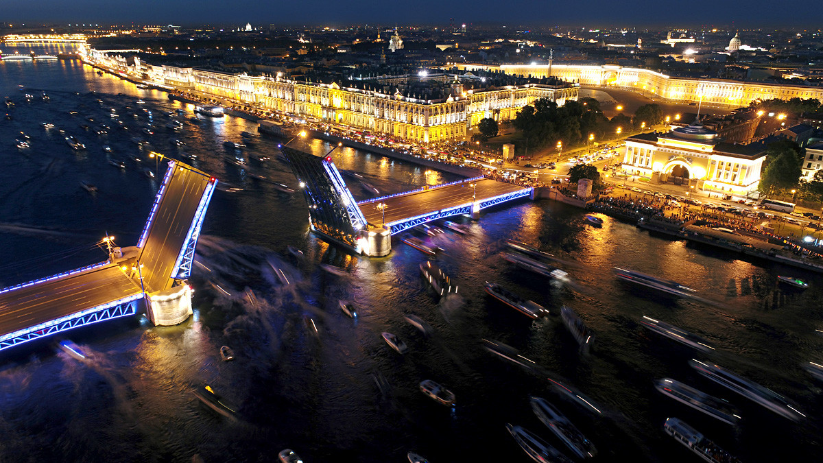 An aerial view of the raised Palace Bridge over the Neva River, the Hermitage Museum, and Palace Square. 