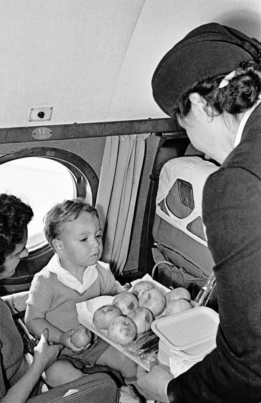 キャビンアテンダントがTu-104の飛行中に機内で乗客にサービスを提供している。1958年。