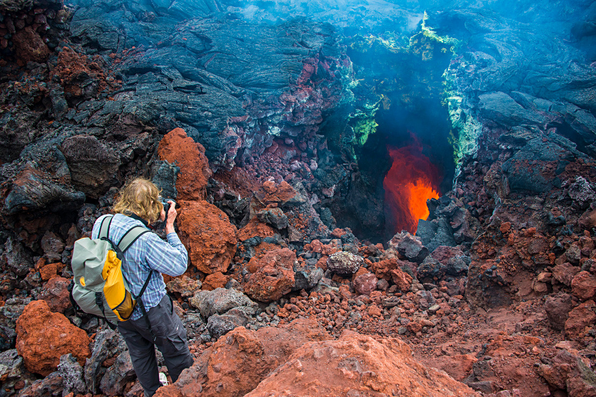 Tourist photographing an active magma stream below the Tolbachik volcano, Kamchatka.