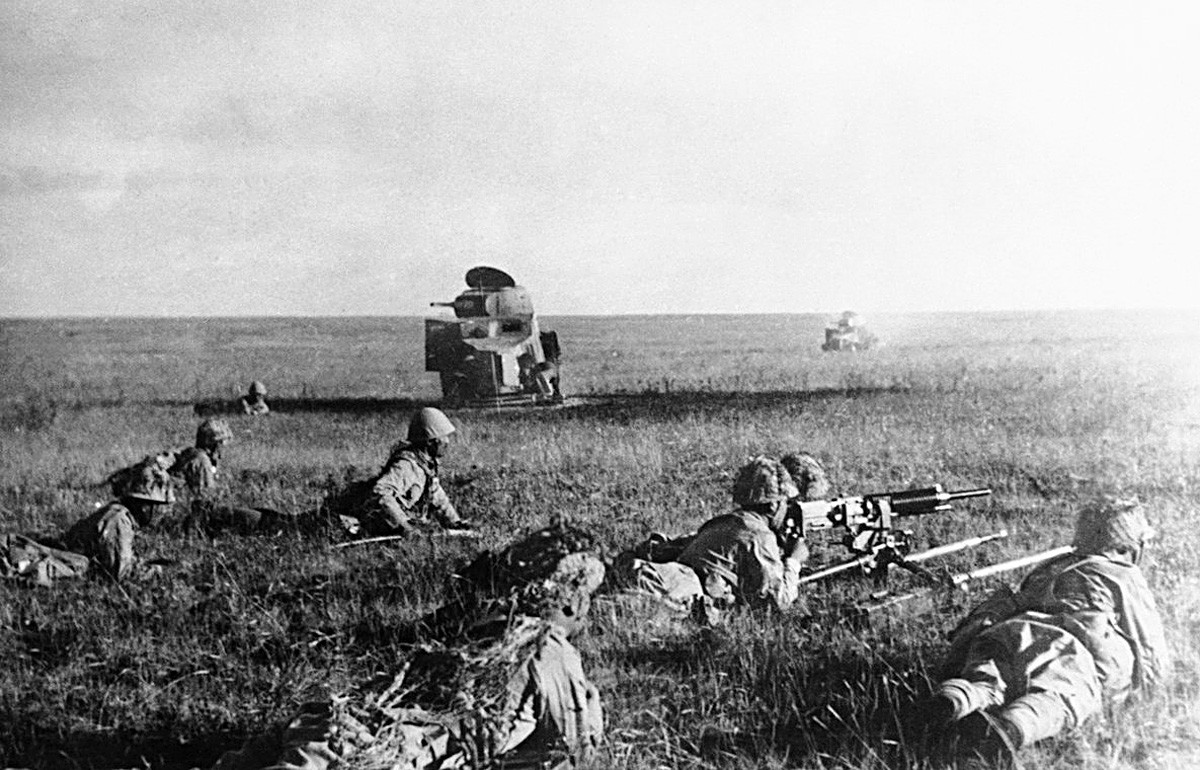Japanische Soldaten kriechen vor zerstörten sowjetischen Panzern.