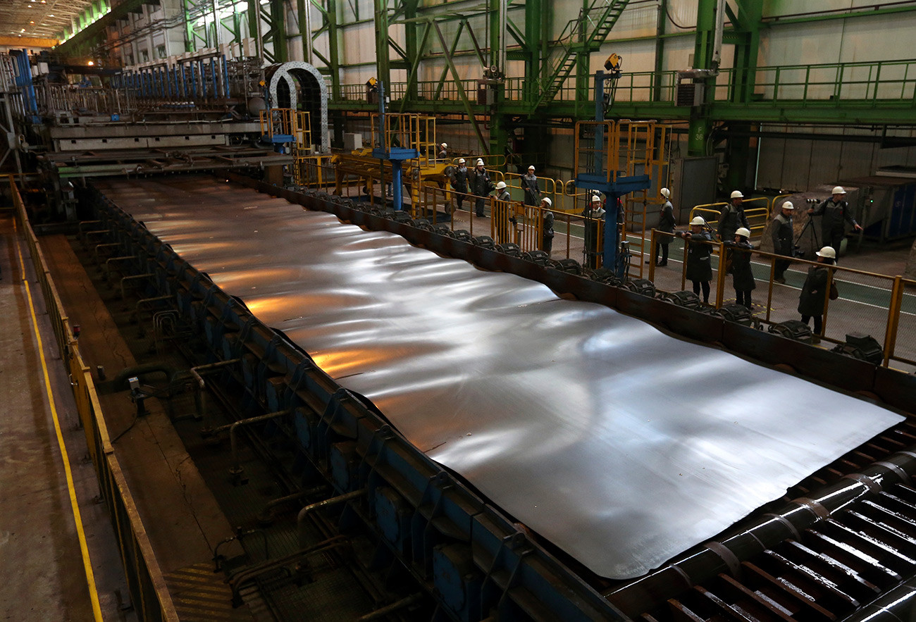Employees stand near a metal sheet at the OMK metal works in Vyksa in the Nizhny Novgorod region.