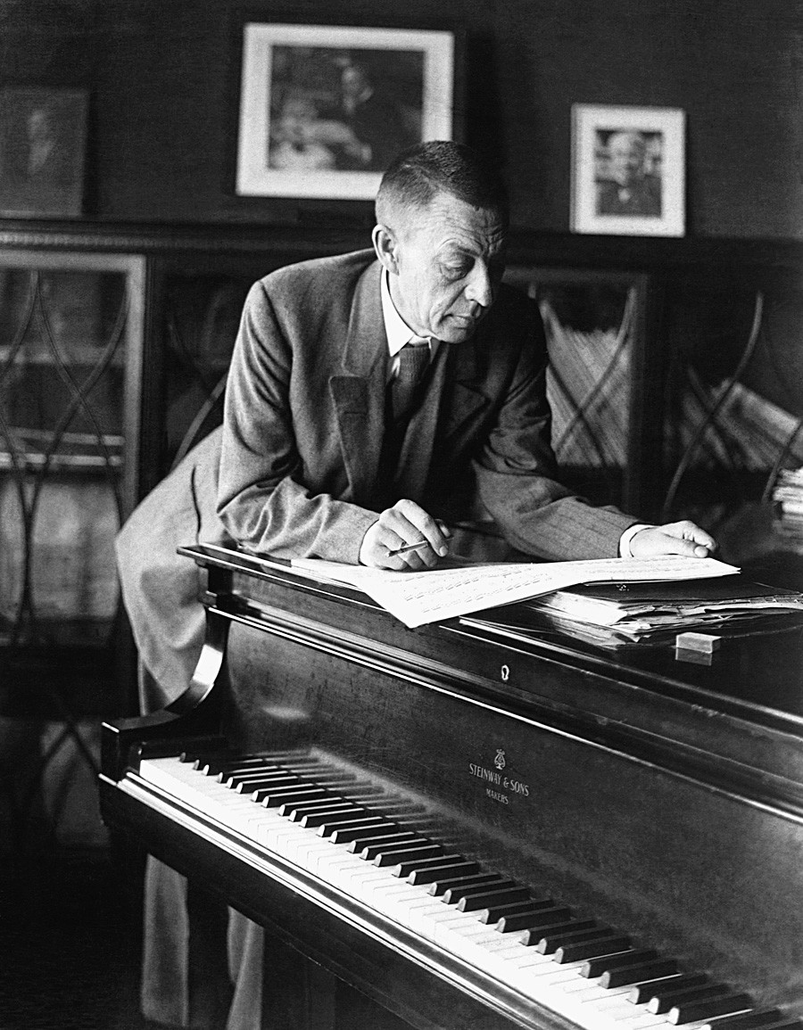 Le compositeur et pianiste d'origine russe Sergueï Rachmaninov (1873-1943) lit une partition musicale au-dessus d'un piano. Années 1920