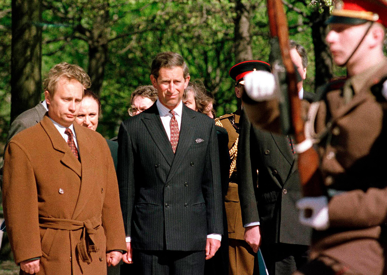 Владимир Путин (лево), кој тогаш бил задолжен за надворешните односи на Санкт Петербург кај градоначалникот Анатолиј Собчак, присуствува на церемонијата на полагање венци со принцот Чарлс на Пискарјовските гробишта во Санкт Петербург, Фотографијата е направена на 17 мај 1994 година.