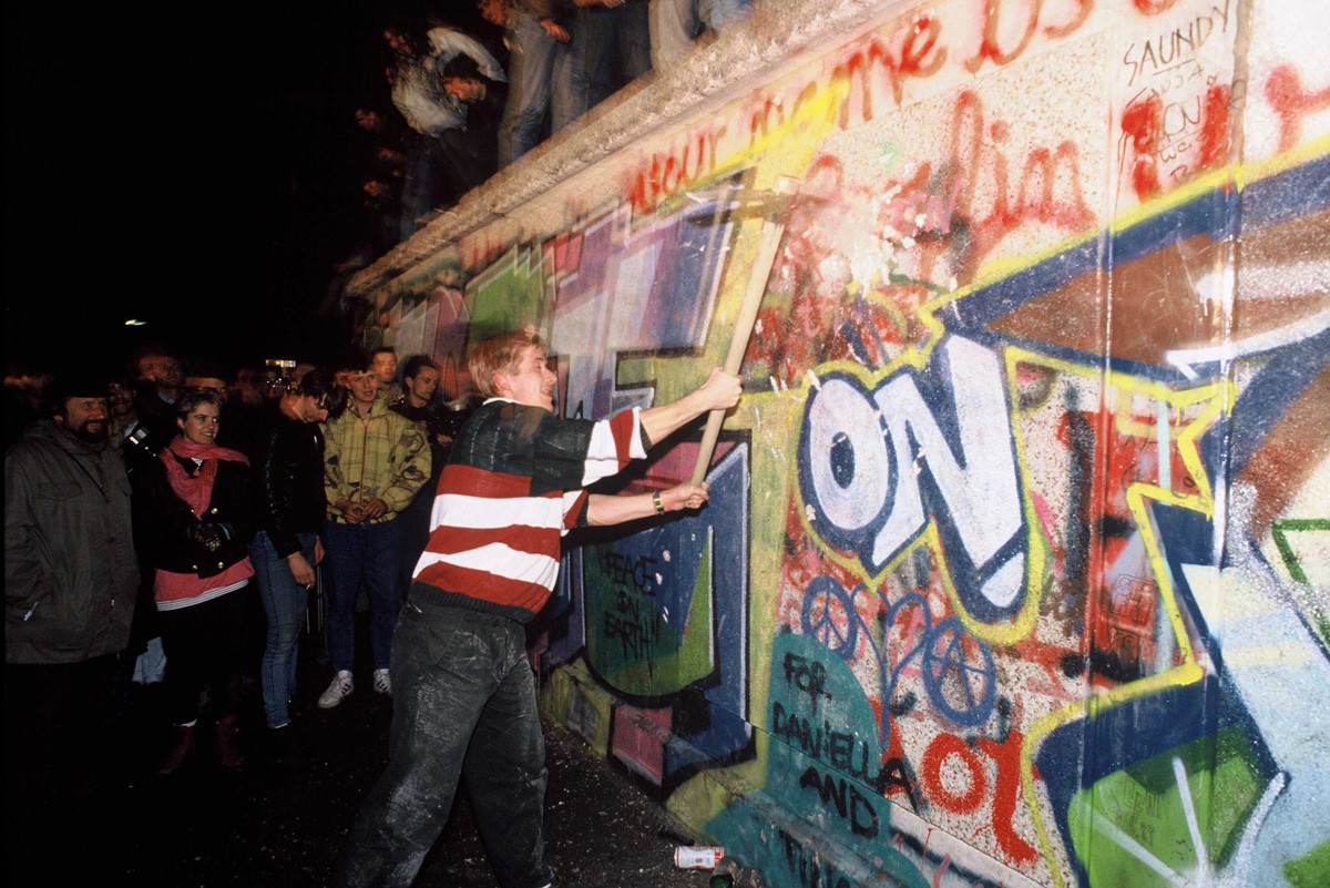 Демонстранты бросаются на стену с кувалдами.