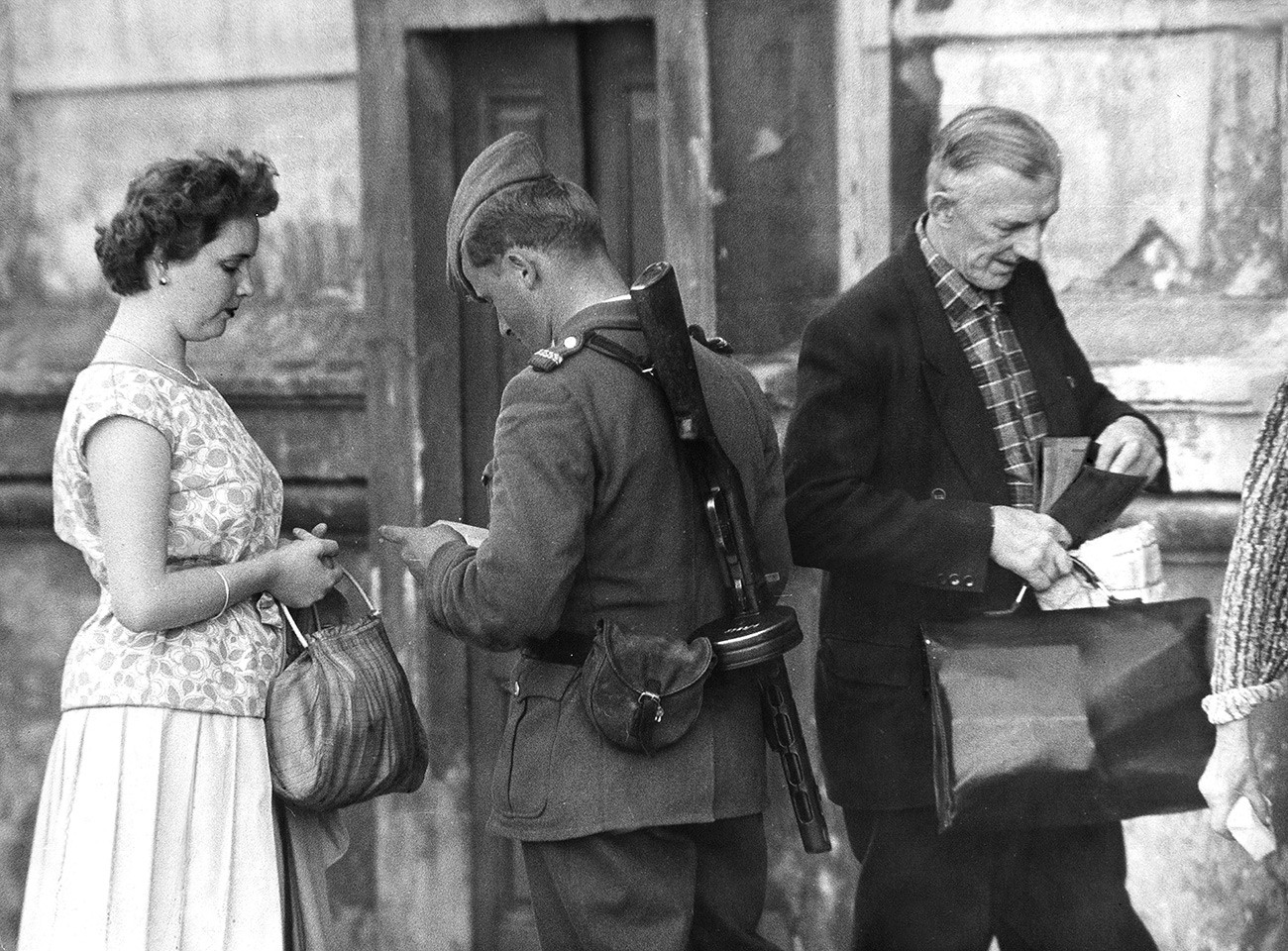 Orang-orang yang tinggal di dekat perbatasan dikontrol oleh polisi Jerman Timur (VOPO) sebelum memasuki flat mereka.