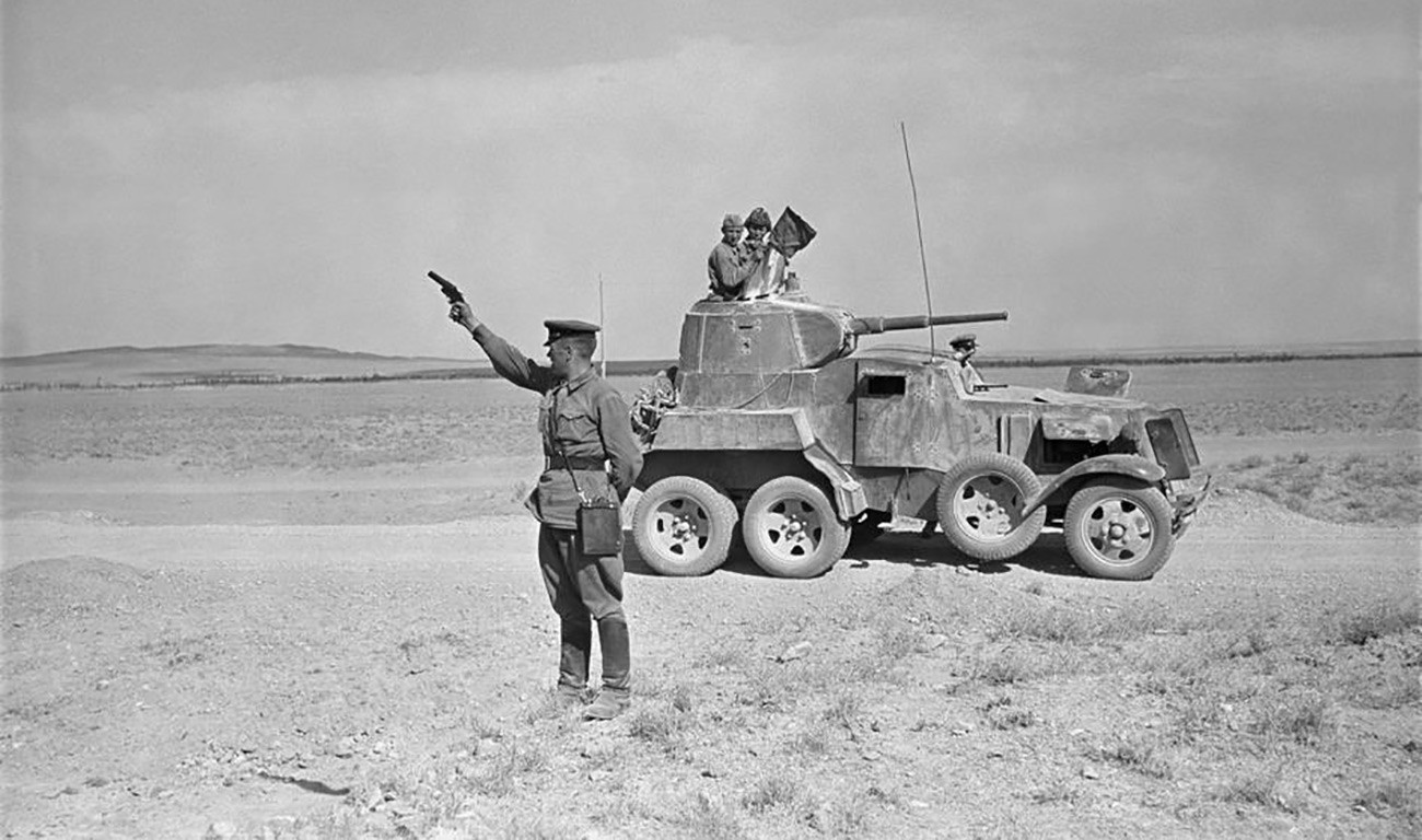 Perwira militer Soviet mengangkat pistol suar, sambil berdiri di gurun Iran.
