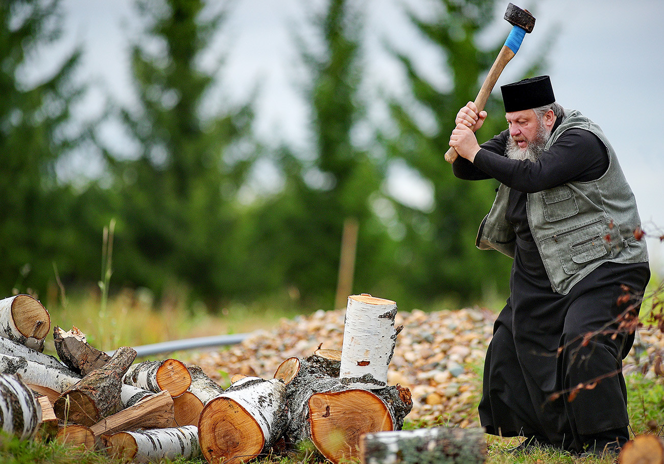 Le prêtre Vladimir Smaglov est en train de couper du bois dans la cour de sa maison. Région d'Ivanovo, ville de Kinechma.