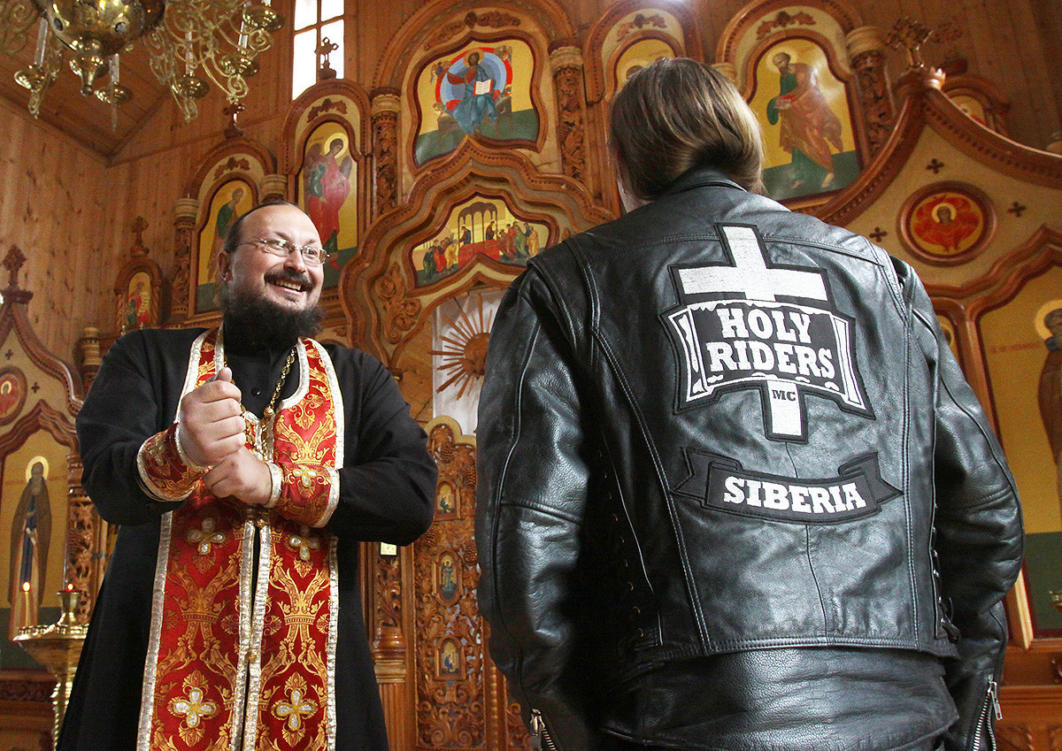 Ruski pravoslavni duhovnik oče Aleksander (L) se pogovarja z bajkerjem v cerkvi v Kemerovu 31. julija 2010. Oče Aleksander, tudi sam navdušen bajker, na leto opravi več verskih bajkerskih romanj v različne cerkve v okolici