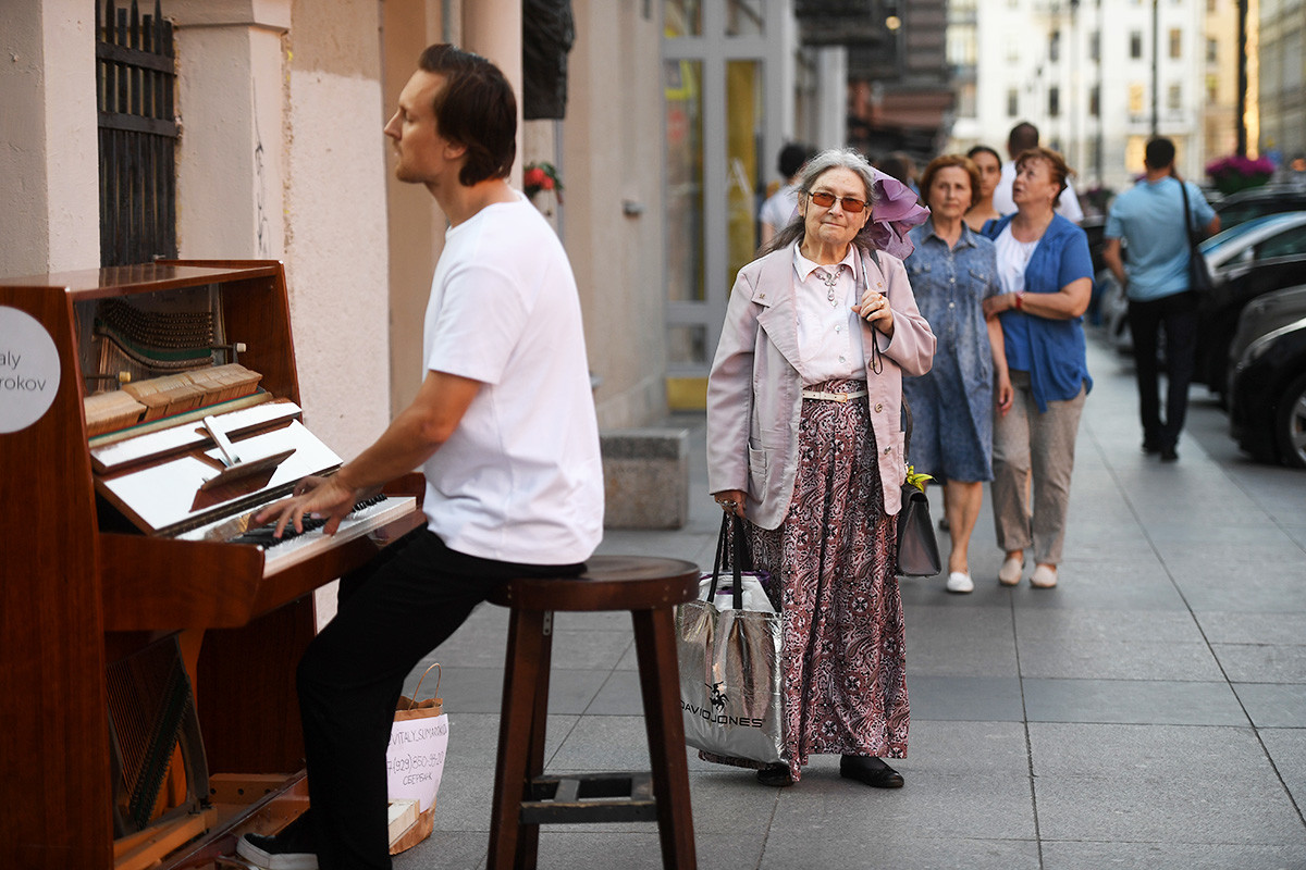Минувачи слушат изпълнение на уличен музикант в Санкт Петербург
