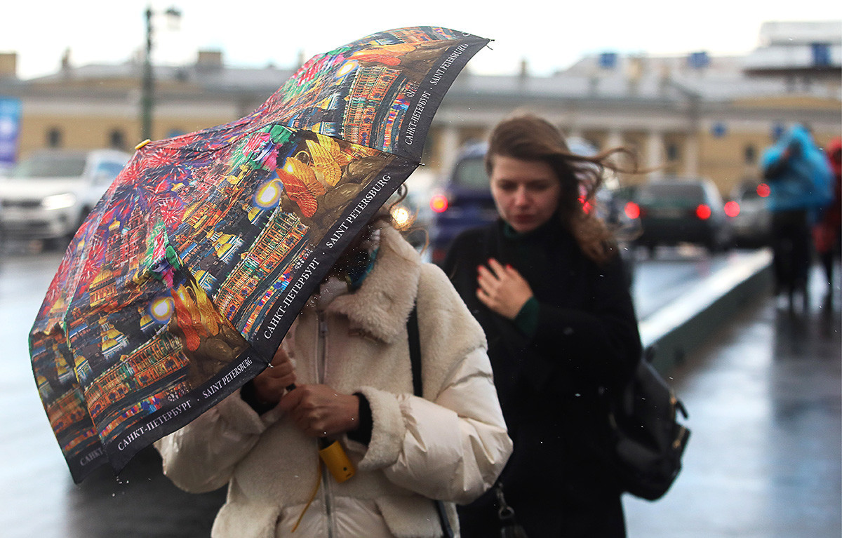 Ljudje v močnem vetru in dežju v centru Sankt Peterburga.