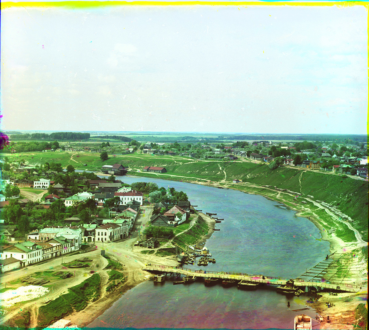 View west up Volga River from Dormition Cathedral bell tower. Middle: Old wooden pontoon bridge with yellow, red & blue smudges indicating movement of horse during three exposures of Prokudin-Gorsky's negative. Left: Prince Dmitry Side. Summer 1910.