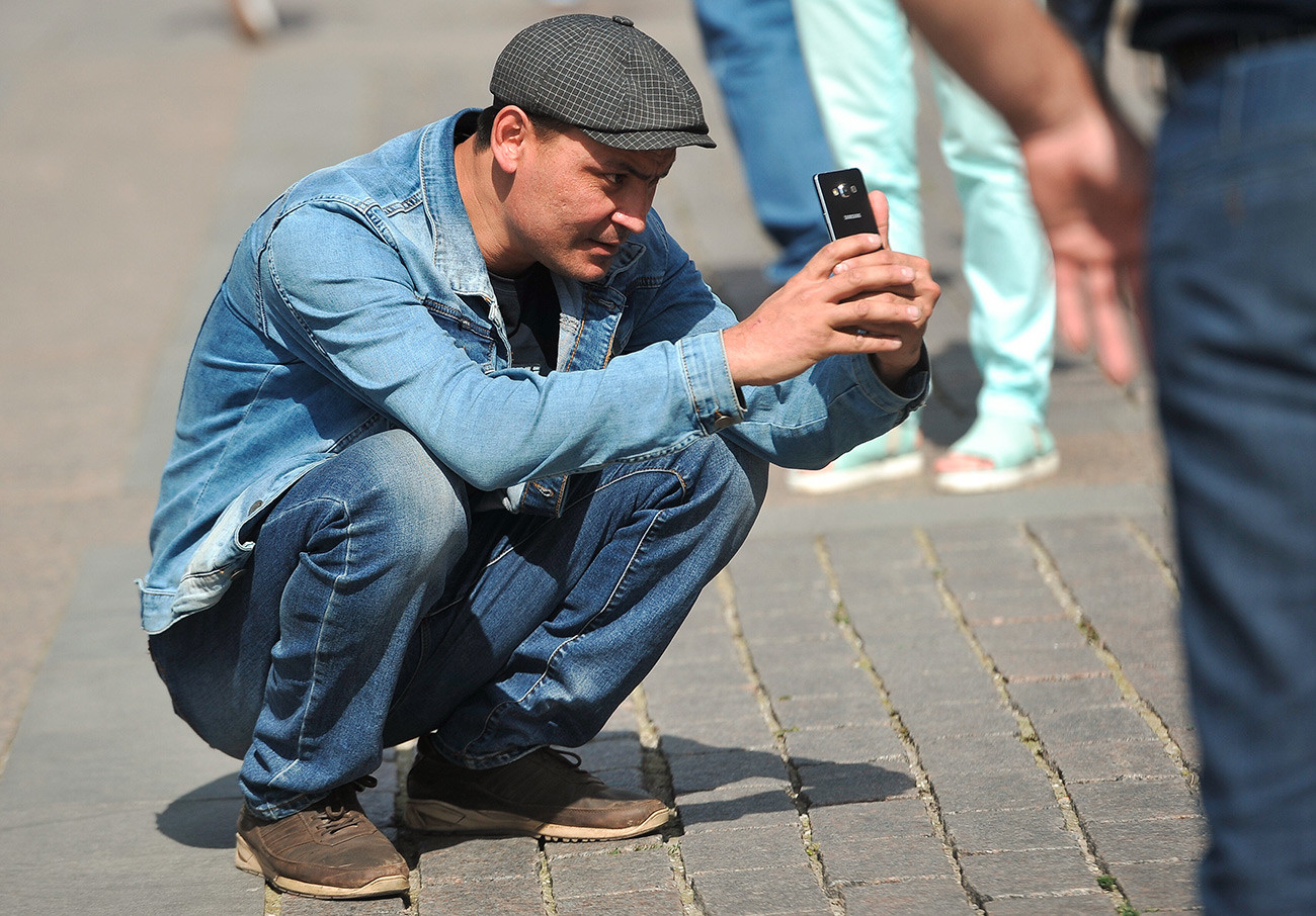 A Russian guy squats to take a picture