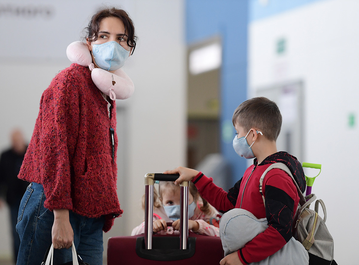 Seorang wanita dan anak-anak mengenakan masker medis setelah tiba dari Kota Sanya, Tiongkok, di Bandara Internasional Vladivostok, Rusia, Jumat (31/1). 