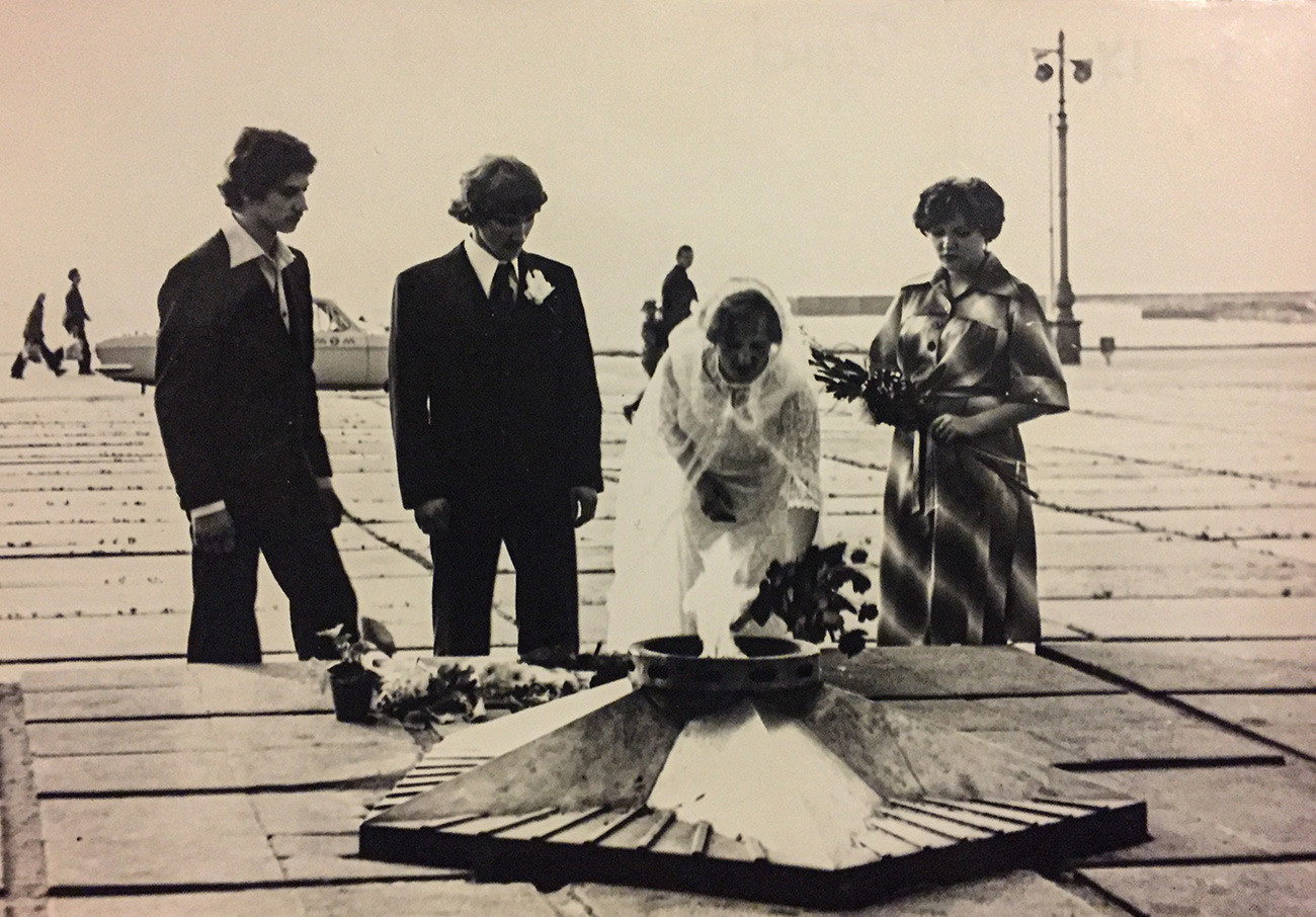 第二次世界大戦で戦ったソ連兵に捧げられる「永遠の火」の横に花を手向ける新郎新婦と証人たち。