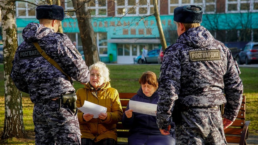 Soldados da Guarda Nacional da Rússia falam com idosos em Moscou.