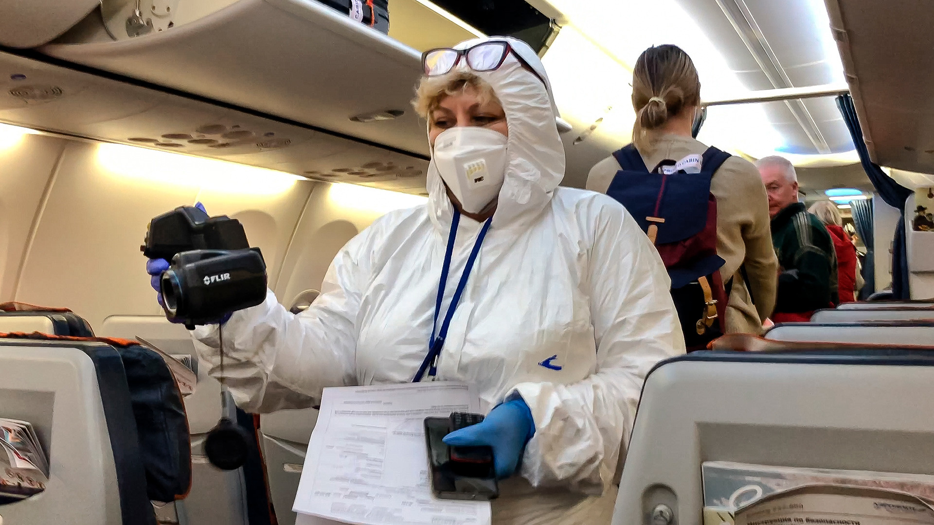 医者がシェレメチェヴォ空港に到着した飛行機で乗客の体温を測っている、2020年3月8日
