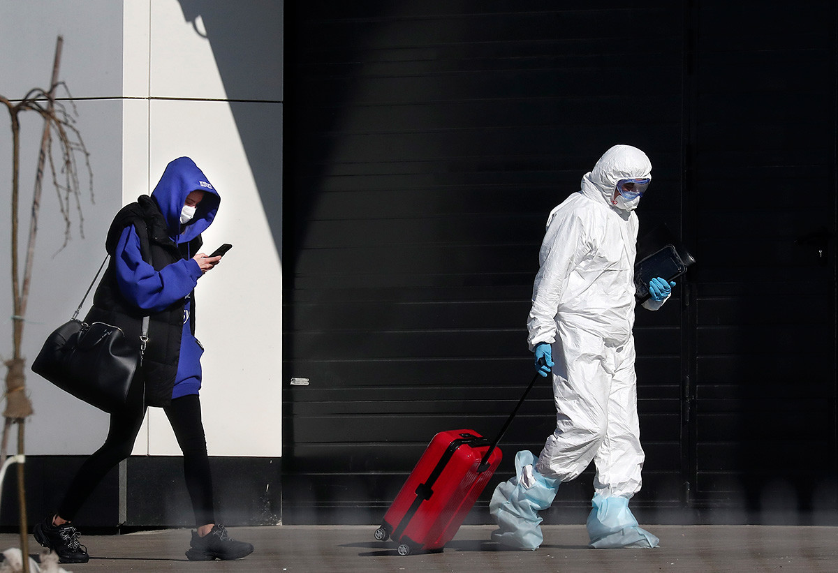 Медицински работник ѝ помага на жена за која се сомнева дека има коронавирус, носејќи ги нејзините работи во подмосковска болница, Русија, вторник, 17 март 2020.

