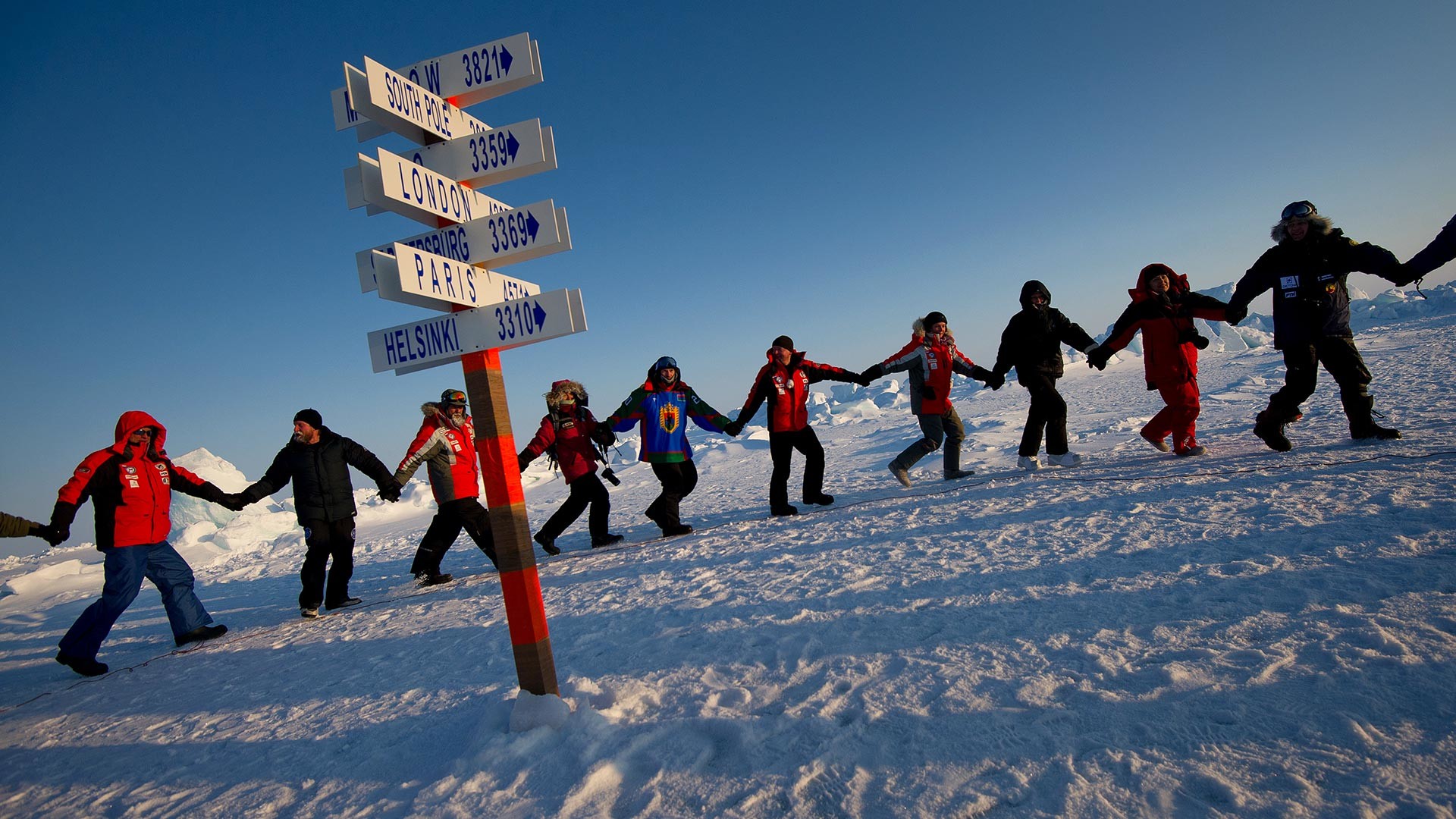 Les participants de l'expédition Carélie – Pôle Nord – Groenland dansant autour du poteau symbolique désignant le Pôle Nord.
