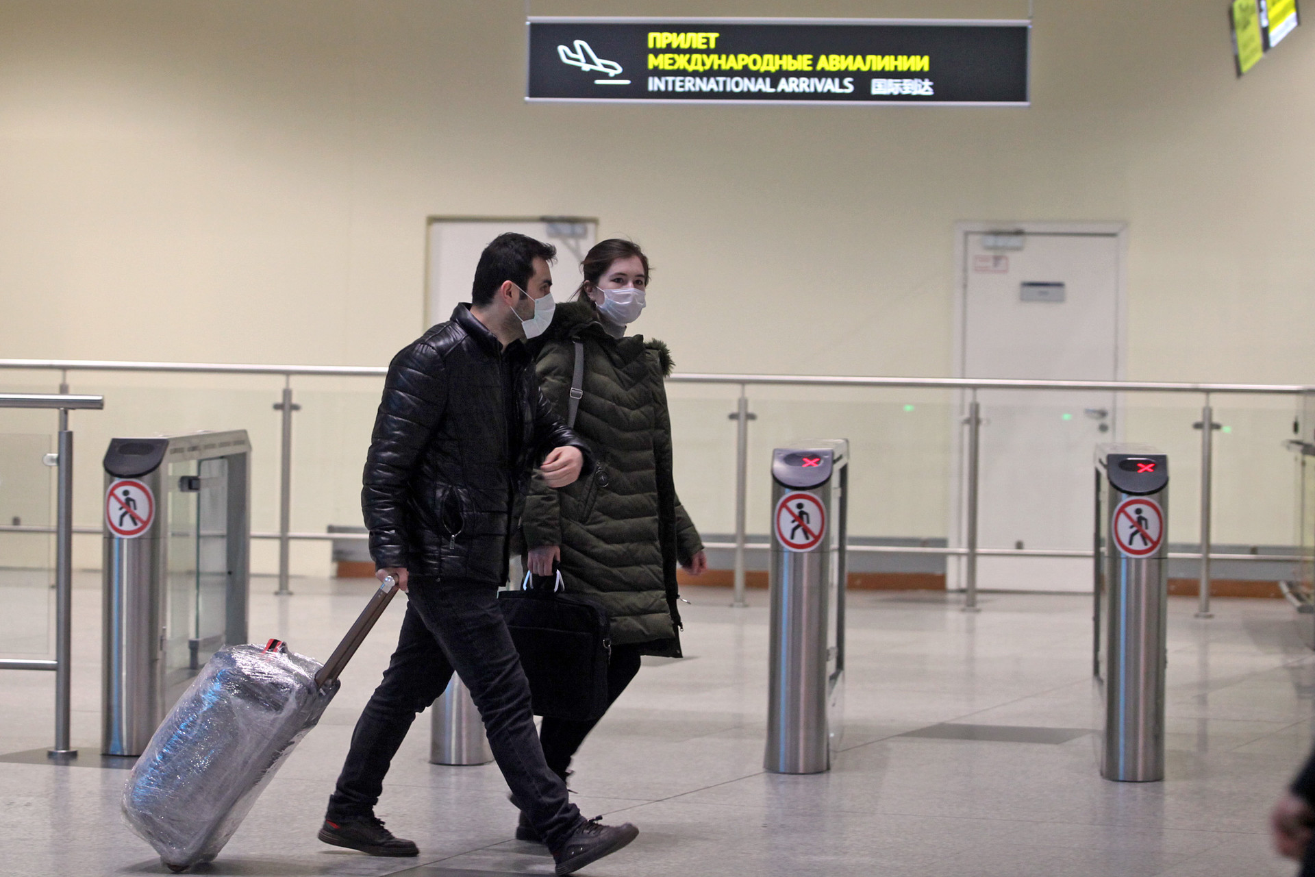 Dua penumpang melintas di dekat pintu kedatangan internasional pada hari pertama pemberlakuan pembatasan masuk warga asing di Bandara Internasional Domodedovo, Moskow, Rabu (18/3).