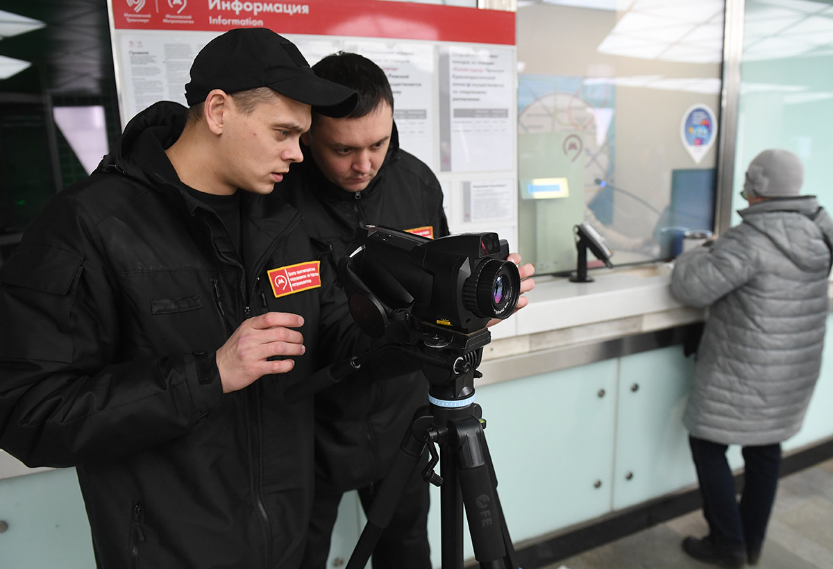 モスクワ地下鉄の駅員が赤外線カメラを使い、乗客の体温を監視する