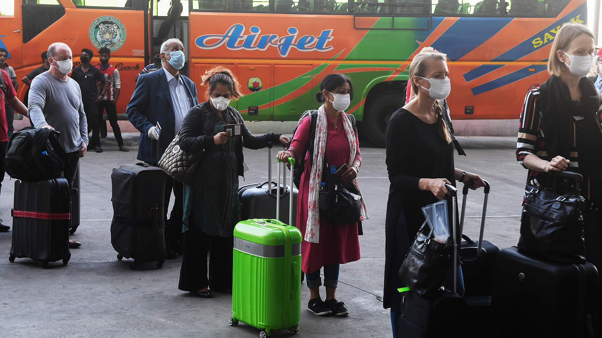 Foreign nationals wearing facemasks line up outside the departure terminal of the Netaji Subhash Chandra Bose International Airport