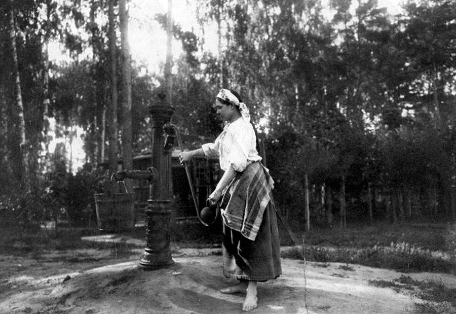 Eine Frau beim Wasserholen an einer Pumpstation