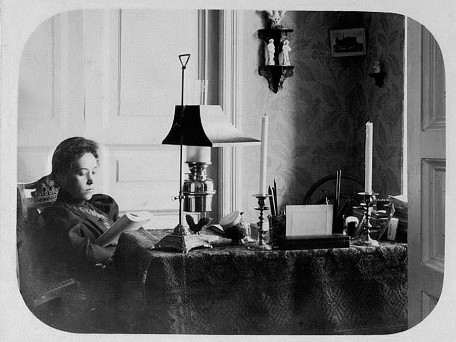 Seorang perempuan membaca buku di rumah.