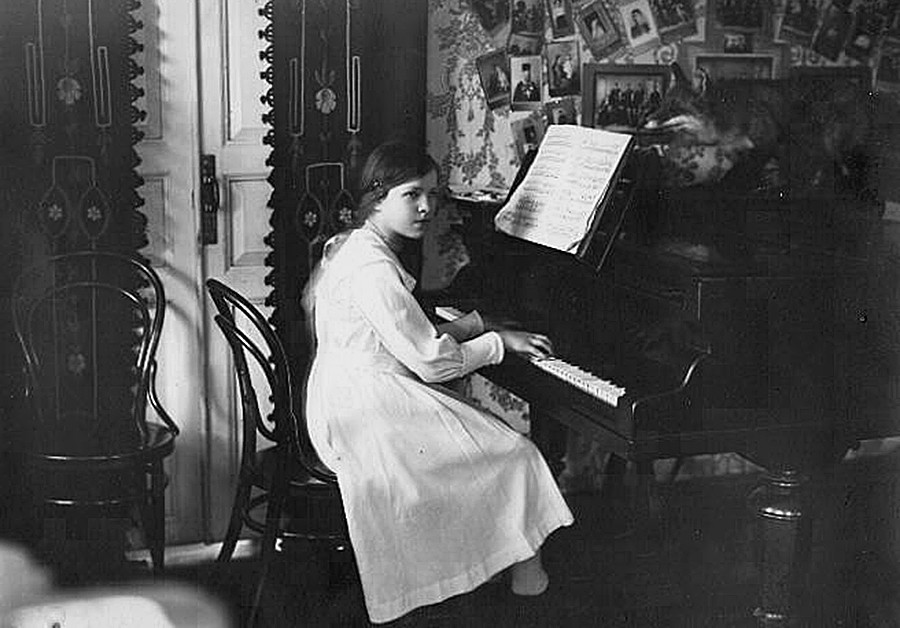 Seorang gadis memainkan piano di rumah.